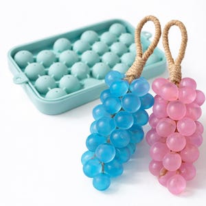 May include: A light blue silicone ice ball mold and two decorative grape clusters. One cluster is blue, the other is pink, both with rope handles. The ice ball mold has 33 round cavities.