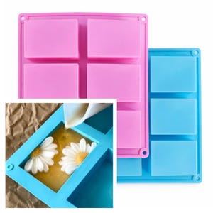 May include: Pink and blue silicone soap molds. The pink mold has four rectangular cavities, while the blue mold has three. A close-up shows a blue mold with daisies being filled with liquid soap.