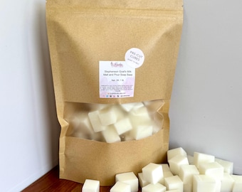 May include: A kraft paper bag with a clear window filled with pre-cut, white soap cubes. A label reads "Stephenson Goat's Milk Melt and Pour Soap Base." A small pile of cubes sits in front of the bag. The net weight is 1 lb.