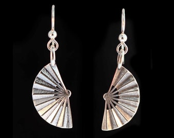May include: A pair of silver earrings with a fan-shaped design. The earrings are made of metal and have a shiny finish.