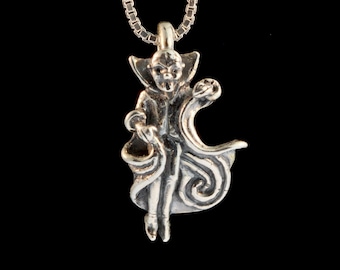 May include: A silver necklace with a pendant of a small, detailed figure of a creature with a cape and a swirling design. The creature has a pointed hat and a mischievous expression.