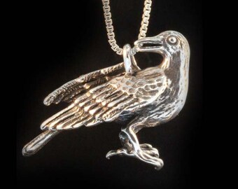 May include: A silver crow pendant necklace with a detailed design. The crow is perched with its wings spread and its head turned to the side. The necklace is on a silver chain.