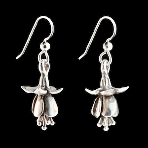 May include: A pair of silver earrings shaped like fuchsia flowers. The earrings have a delicate, floral design and are perfect for adding a touch of elegance to any outfit.