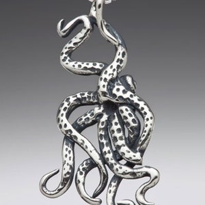 May include: A silver octopus pendant necklace with a textured surface. The octopus is depicted with its tentacles curled up.