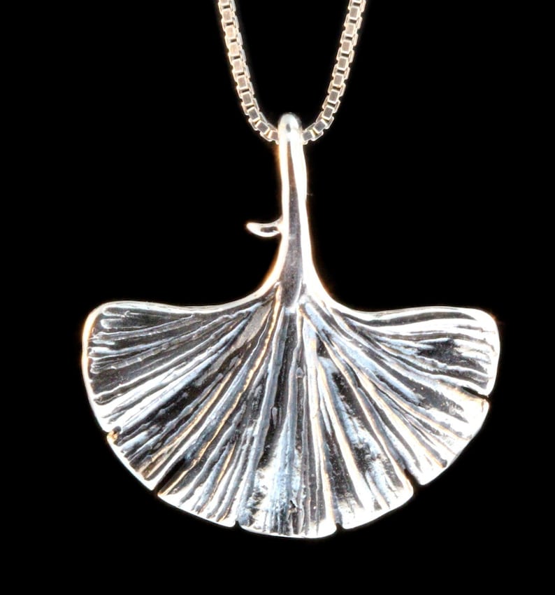 May include: A silver pendant necklace featuring a detailed ginkgo leaf design. The pendant is attached to a silver chain.