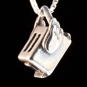 May include: A silver charm necklace featuring a detailed miniature toaster with wings. The charm is attached to a silver chain.