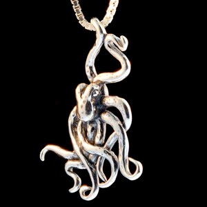 May include: A silver octopus pendant with a detailed, textured design. The pendant is hanging from a silver chain.