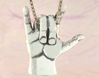 May include: Silver necklace with a pendant shaped like a hand making the American Sign Language sign for 'I love you'.