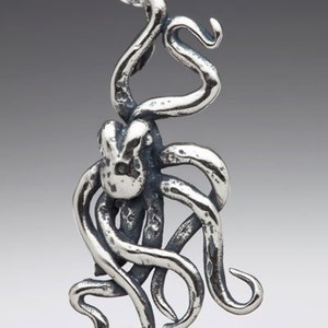May include: A silver octopus pendant necklace with a detailed, textured design. The octopus is curled up with its tentacles intertwined.