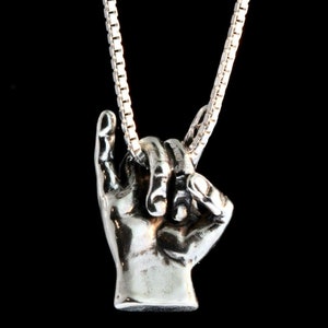 May include: A silver necklace with a pendant shaped like a hand making the 'I love you' sign in American Sign Language.