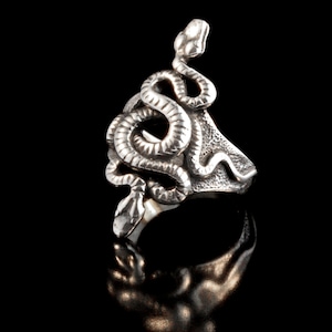 Op de afbeelding: Een zilveren ring met een gedetailleerd slangendesign. De slang is opgerold en zijn kop is opgeheven, met een licht geopende mond. De ring is gemaakt van sterling zilver en heeft een gepolijste afwerking.