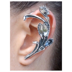 May include: Silver ear cuff with a floral design. The cuff features a delicate, intricate design with multiple leaves and flowers. The ear cuff is made of metal and has a polished finish.
