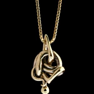 May include: A gold chain necklace with a gold pendant in the shape of a knot.