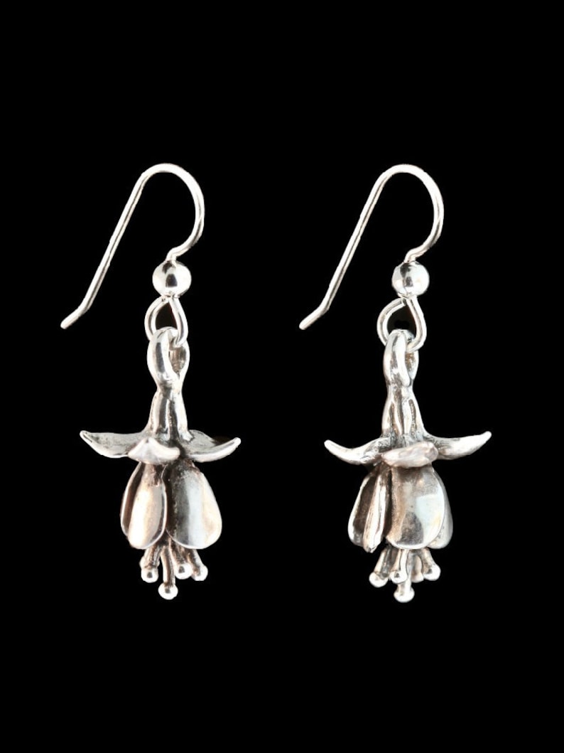 May include: A pair of silver earrings shaped like fuchsia flowers. The earrings have a delicate, floral design and are perfect for adding a touch of elegance to any outfit.
