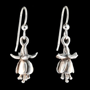 May include: A pair of silver dangle earrings featuring a detailed fuchsia flower design.
