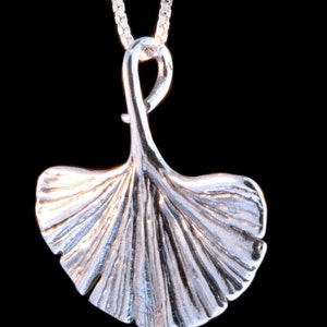 May include: A silver pendant necklace featuring a detailed ginkgo leaf design. The pendant is attached to a silver chain.