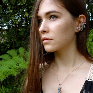 Puede incluir: Una mujer con el pelo largo y casta&ntilde;o que lleva un collar de plata con un colgante detallado y un pendiente de plata en forma de pulpo.