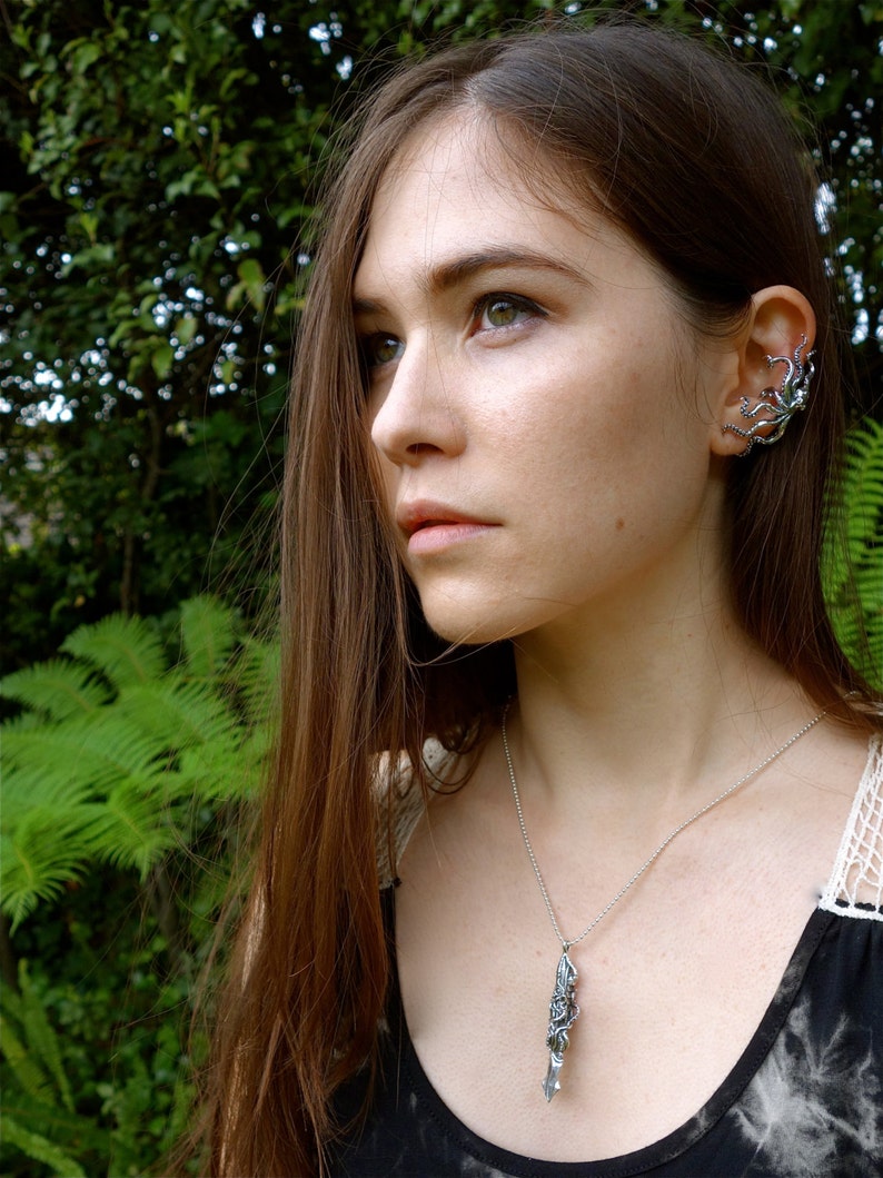 Puede incluir: Una mujer con el pelo largo y casta&ntilde;o que lleva un collar de plata con un colgante detallado y un pendiente de plata en forma de pulpo.