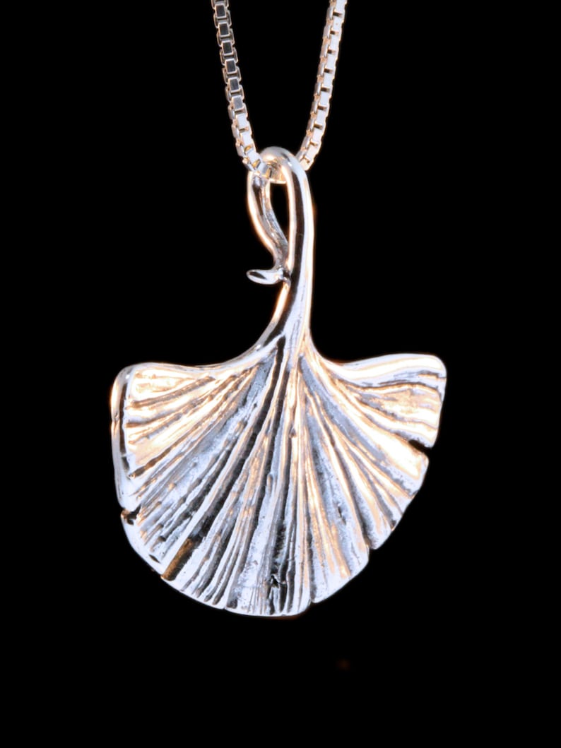 May include: A silver pendant necklace featuring a detailed ginkgo leaf design. The pendant is attached to a silver chain.