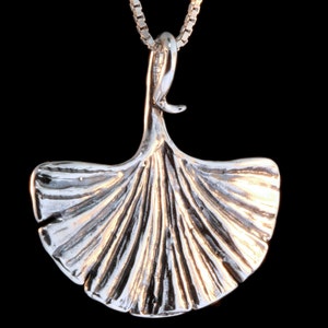 May include: A silver pendant necklace featuring a detailed ginkgo leaf design. The pendant is attached to a silver chain.