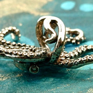 Puede incluir: Un anillo de plata con forma de pulpo con tent&aacute;culos detallados. El anillo est&aacute; dise&ntilde;ado para parecer un pulpo con sus tent&aacute;culos enroscados alrededor de la banda del anillo.