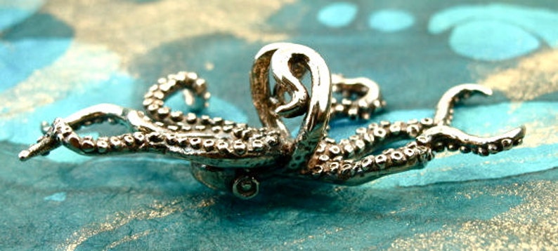 Puede incluir: Un anillo de plata con forma de pulpo con tent&aacute;culos detallados. El anillo est&aacute; dise&ntilde;ado para parecer un pulpo con sus tent&aacute;culos enroscados alrededor de la banda del anillo.