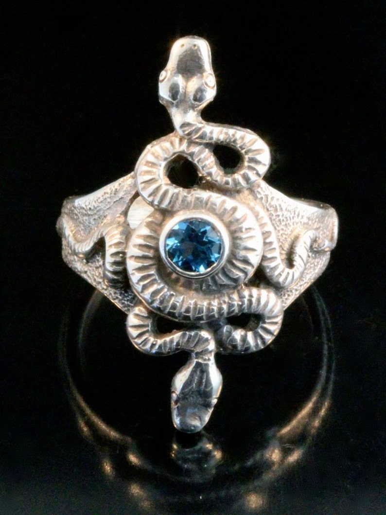 May include: A silver ring featuring a detailed snake design with a blue gemstone in the centre.