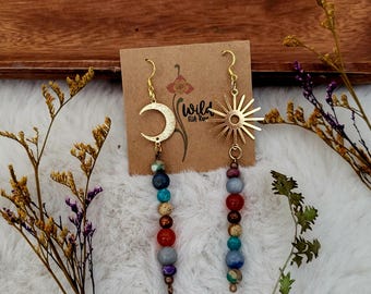 May include: Gold earrings with a crescent moon and a sunburst charm. Each earring features a beaded dangle with blue, red, and brown beads.