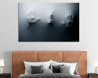 May include: A black and white abstract art print of a face and hands emerging from a white surface. The print is framed and hanging on a white wall above a brown leather headboard.