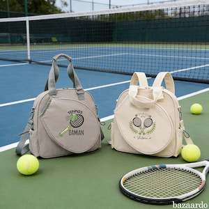 Può includere: Due borse da tennis, una grigia e una color crema, con grafiche di palline e racchette da tennis. La borsa grigia ha stampato "Tennis" e "Damian". La borsa color crema ha stampato "Tennis" e "Victoria". Sono visibili anche palline da tennis e una racchetta.