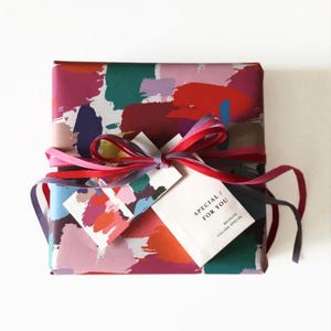 May include: A gift wrapped in colorful abstract patterned paper with a red, pink, blue, and purple ribbon. The gift tag reads "Special for you because you are special."