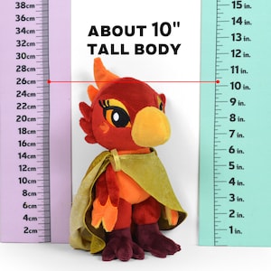 May include: A red, orange, and yellow plush toy bird with a green cape. The toy is about 10 inches tall and is standing next to a ruler. "ABOUT 10" TALL BODY" is written above the toy.