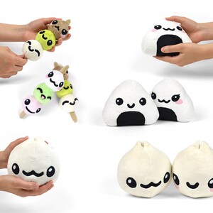 Pu&ograve; includere: Un set di peluche a forma di cibo giapponese. Il set include un dango, un onigiri e un bao. I peluche sono tutti bianchi con occhi e bocche neri, e alcuni hanno le guance rosa.