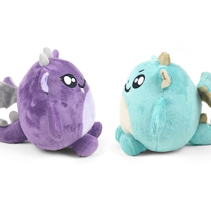 Peut inclure: Deux peluches en forme de dragon, l'une violette et l'autre bleue, avec de grands yeux et des ailes.