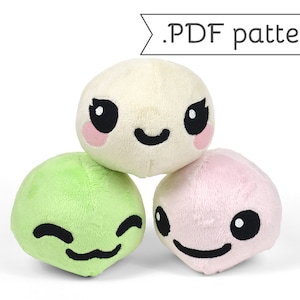 Puede incluir: Tres juguetes mochi de peluche con caras de dibujos animados. Los mochi son blancos, verdes y rosas.