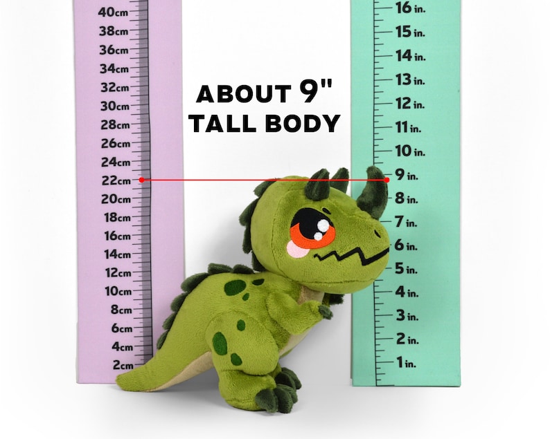 Puede incluir: Juguete de dinosaurio de peluche verde con ojos rojos y un cuerno en la cabeza. El juguete mide aproximadamente 23 cm de alto y se mide contra una regla.