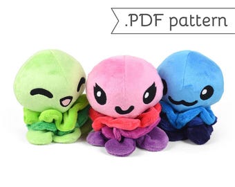 May include: Three plush toys shaped like jellyfish, each with a different color and facial expression. The jellyfish are green, pink, and blue. The green jellyfish has a happy expression, the pink jellyfish has a mischievous expression, and the blue jellyfish has a surprised expression.