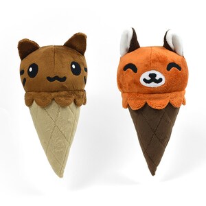 May include: Two plush ice cream cones with animal faces. The first cone is brown with a cat face and the second cone is orange with a fox face.