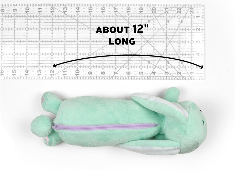 May include: A light green plush bunny pencil case with a purple zipper. The pencil case is approximately 12 inches long.