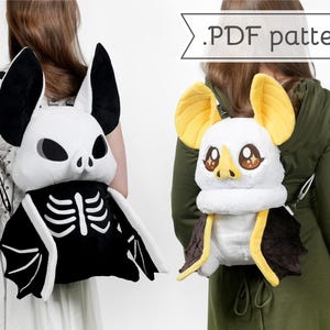 Puede incluir: Dos mochilas de murciélago de peluche. Una es blanca y negra con un diseño de esqueleto, la otra es blanca con orejas amarillas y detalles marrones. El texto ".PDF pattern" está encima de la segunda mochila.