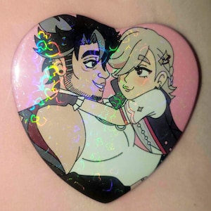 May include: Heart-shaped button featuring a couple embracing, with a pink background and holographic accents. The illustration depicts two figures with detailed facial features and clothing, creating a romantic theme.