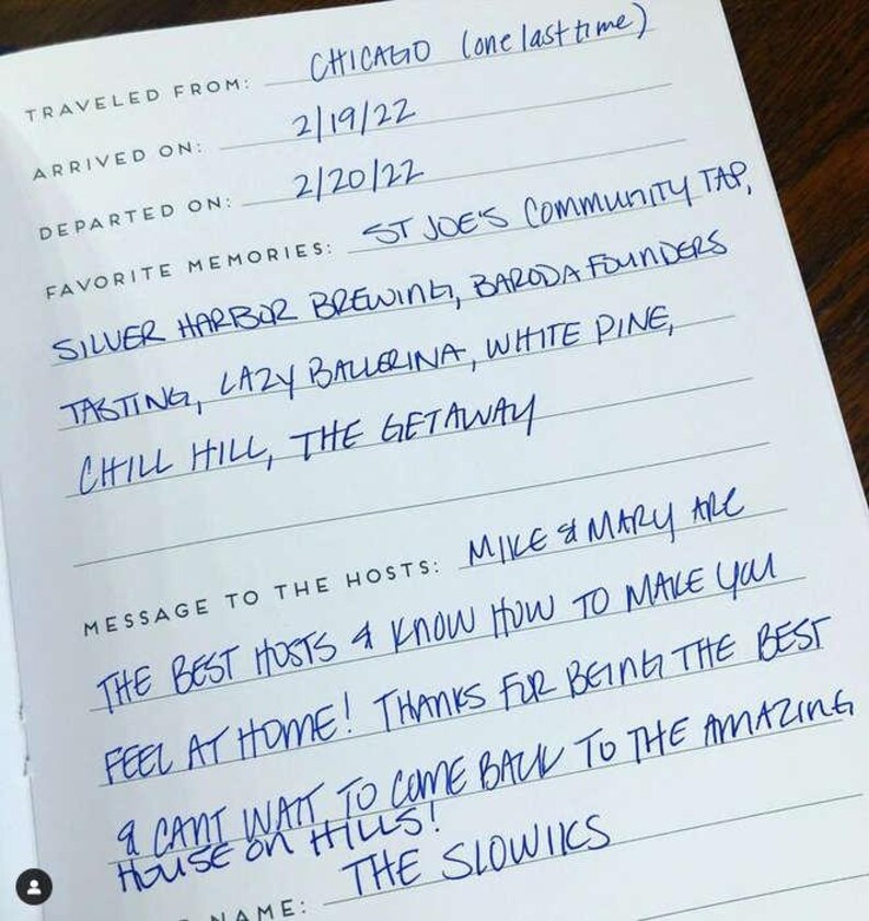 May include: A white guestbook page with blue ink handwriting. Fields include Traveled From: Chicago, Arrived On: 2/19/22, Departed On: 2/20/22. Favorite memories listed are St Joe's Community Tap, Silver Harbor Brewing, Baroda Founders, Tasting, Lazy Ballerina, White Pine, Chill Hill, The Getaway. Message to the hosts: Mike & Mary are the best hosts & know how to make you feel at home! Thanks for being the best & cant wait to come back to the amazing house on hills! The Slowiks.