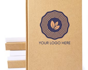 May include: A tan hardcover notebook with a dark blue circular logo featuring concentric wavy lines and three leaves in the center. The text "YOUR LOGO HERE" is printed in dark blue below the logo. A stack of small tan and white blocks sits nearby.