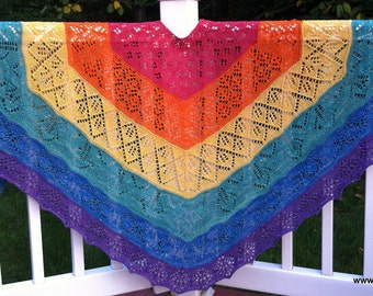 May include: A rainbow colored crocheted shawl with a lacy pattern. The shawl is draped over a white railing.