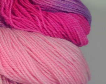 May include: Close-up of a pile of yarn in shades of pink, purple, and white. The yarn is soft and fluffy, and it would be perfect for knitting or crocheting.