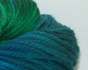 May include: A skein of yarn in a gradient of teal and green colors. The yarn is soft and fluffy, and it is perfect for knitting or crocheting.