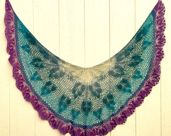 May include: A teal, purple, and cream crocheted shawl with a leaf pattern. The shawl has a scalloped edge.