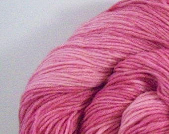 May include: A skein of pink yarn with a gradient of color from a lighter pink to a darker pink.