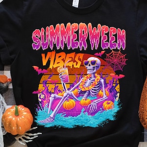 Könnte beinhalten: Schwarzes T-Shirt mit einem farbenfrohen Grafikdesign. Es zeigt ein Skelett mit Sonnenbrille und Blumenkette, das auf einem Schwimmreifen mit Kürbissen entspannt. Der Text "SUMMERWEEN VIBES" ist über dem Skelett abgebildet.
