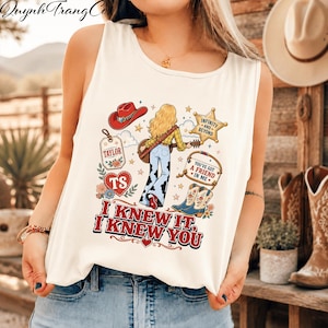 May include: A white sleeveless tank top featuring a graphic print of a blonde person with a guitar, a red cowboy hat, a star badge with text Infinity and Beyond, a tag labelled Taylor, a heart labelled TS, and boots with the text You've Got A Friend In Me.